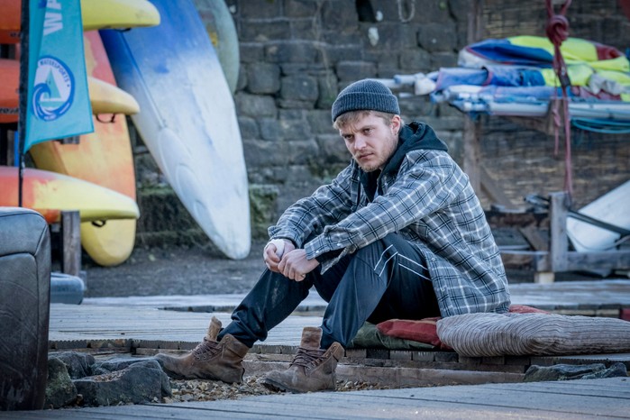 Tom Glynn-Carney as Malachy in The Jetty Tom Glynn-Carney as Malachy in The Jetty sitting in a chequered shirt and woolly hat