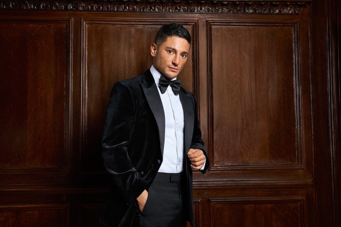Reza for Made in Chelsea season 27 Reza wearing a tuxedo, being pictured for Made in Chelsea season 27. He has one hand in his pocket and the other above.