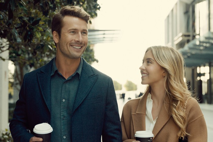 Anyone But You Anyone But You Glen Powell and Sydney Sweeney walking together with coffee cups smiling