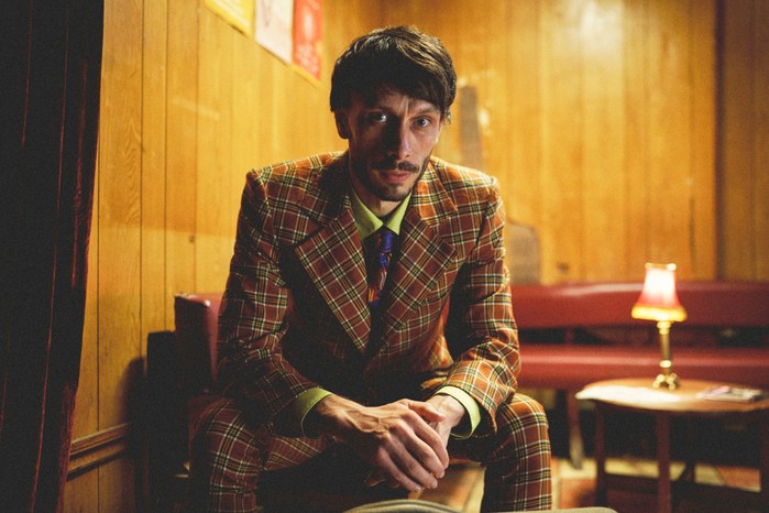 Baby Reindeer, Netflix Donny sat down, leaning slightly forward, dressed in a suit