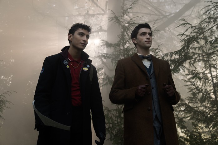 Jayden Revri as Charles Rowland and George Rexstrew as Edwin Payne in Dead Boy Detectives Jayden Revri as Charles Rowland and George Rexstrew as Edwin Payne in Dead Boy Detectives standing in a forest as the sun sets