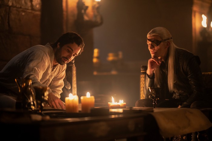 fabien-frankel-ewan-mitchell (1) Fabien Frankel as Ser Criston Cole sits by candlelight with Ewan Mitchell as Prince Aemond Targaryen in House of the Dragon season 2.