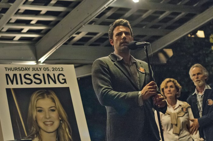 Gone Girl Ben Affleck as Nick Dunne in Gone Girl, stood by a missing poster featuring Amy Elliot Dunne, as played by Rosamund Pike