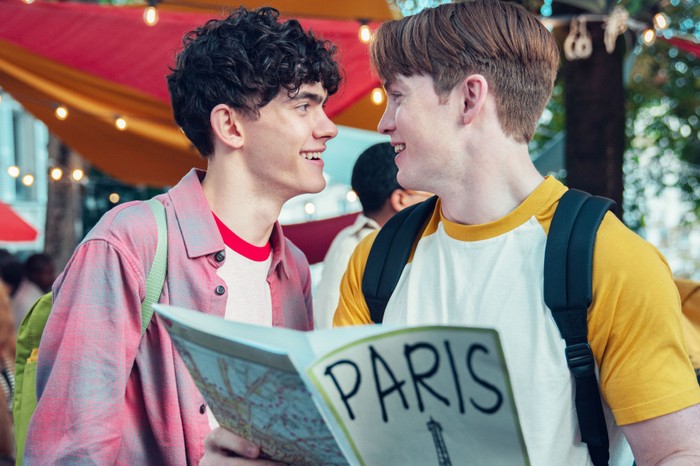 Heartstopper Season 2 Nick and Charlie looking into one another's eyes, with a Paris guidebook in shot