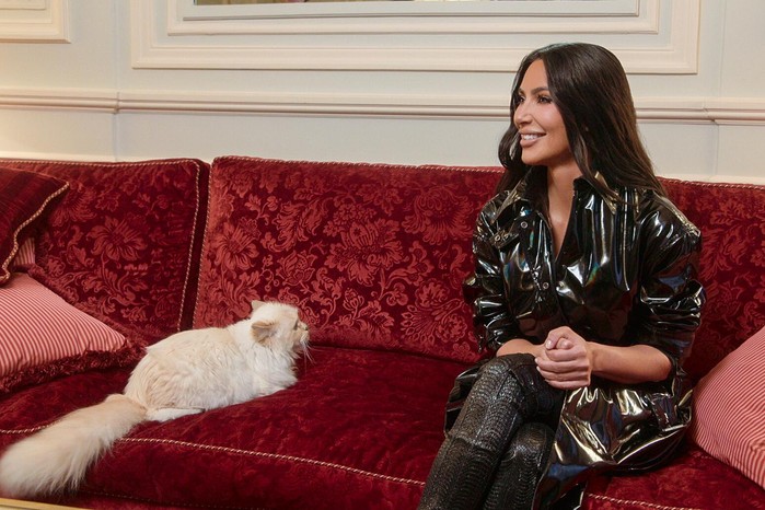 It Takes A Village Kim Kardashian and Choupette sitting on a sofa in The Kardashians.