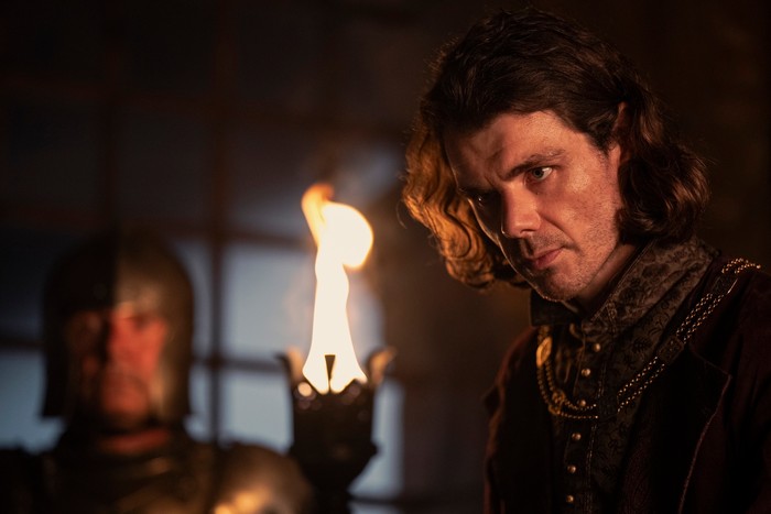 matthew-needham (2) Matthew Needham as Lord Larys Strong against firelight in a castle in House of the Dragon season 2.