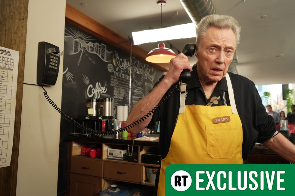 outlaws-season-3-chris-walken Frank (Christopher Walken) wearing a yellow apron while working in a cafe, holding a wired landline phone to his ear