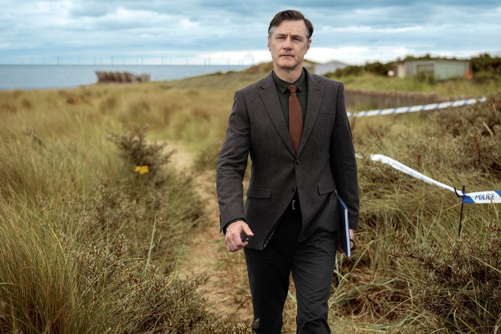 David Morrissey Ian St Clair Sherwood David Morrissey as Ian St Clair in Sherwood, walking along a coastal path in a suit