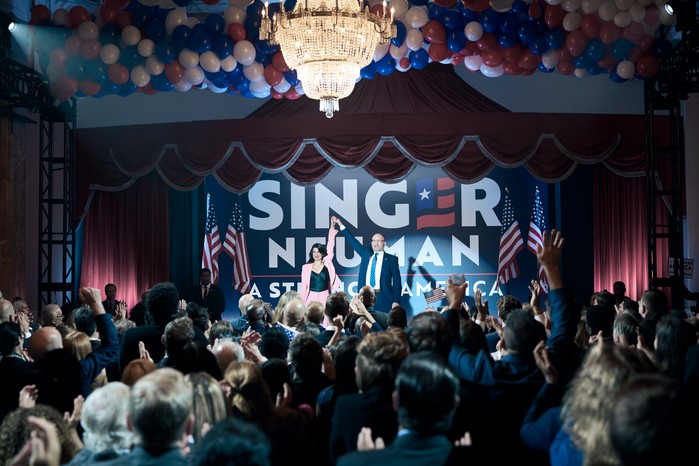 The Boys Season 4 Jim Beaver as Robert Singer and Claudia Doumit as Victoria Neuman in The Boys, stood on a campaign stage together raising their hands in the air together