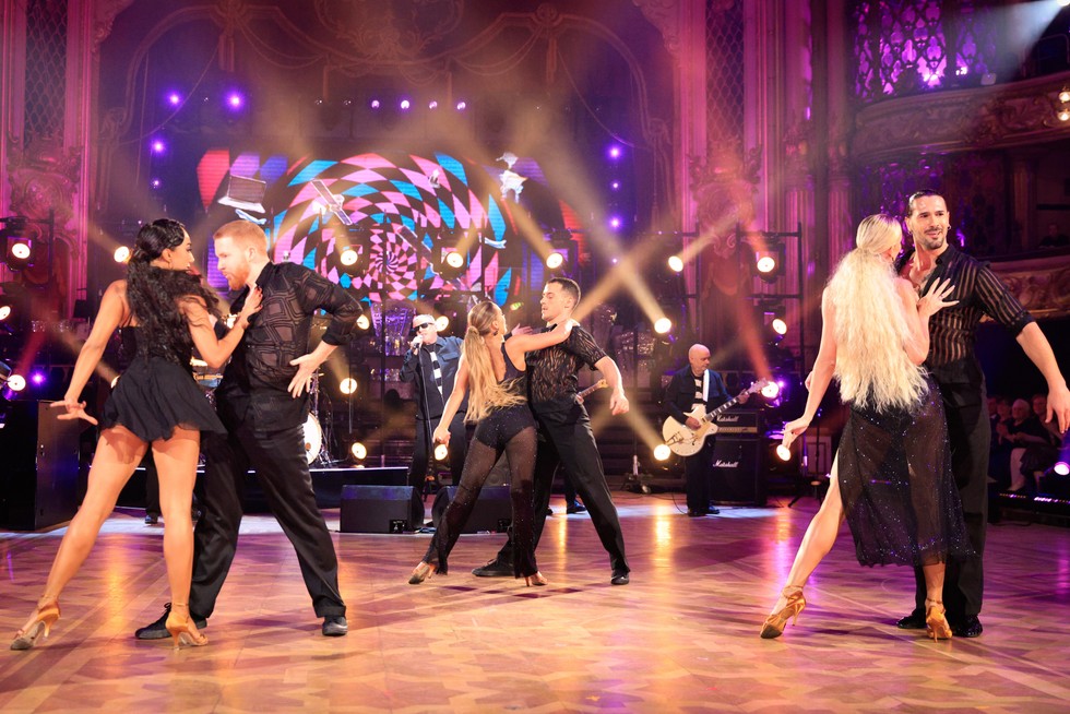 Strictly Come Dancing professionals Strictly Come Dancing professionals dancing in three pairs of two on the ballroom floor, with Madness performing in the background.