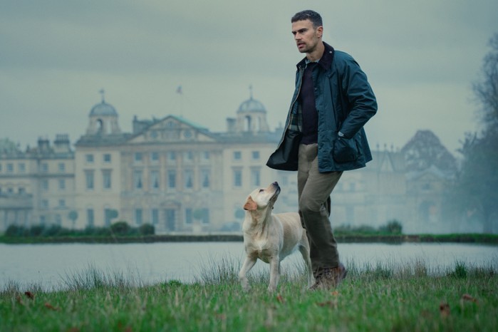 TG_101_Unit_01700RT3.jpg,TG_101_Unit_01700RT3 Theo James in The Gentlemen, walking with a dog on the grounds of a country house