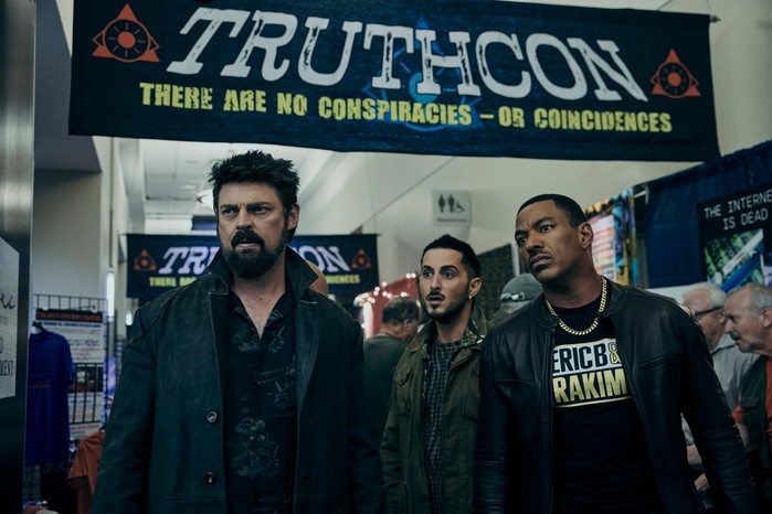 The Boys Season 4 Karl Urban as Billy Butcher, Laz Alonso as Mother's Milk and Tomer Capone as Frenchie in The Boys, stood under a banner which says Truthcon