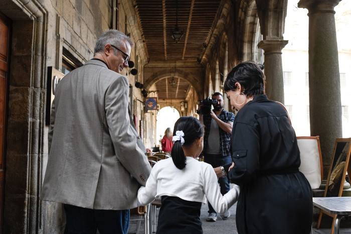 TheAsuntaCase-Netflix-Asunta Tristán Ulloa as Alfonso, Iris Wu as Asunta, Candela Peña as Rosario walking hand in hand through a busy street in The Asunta Case.
