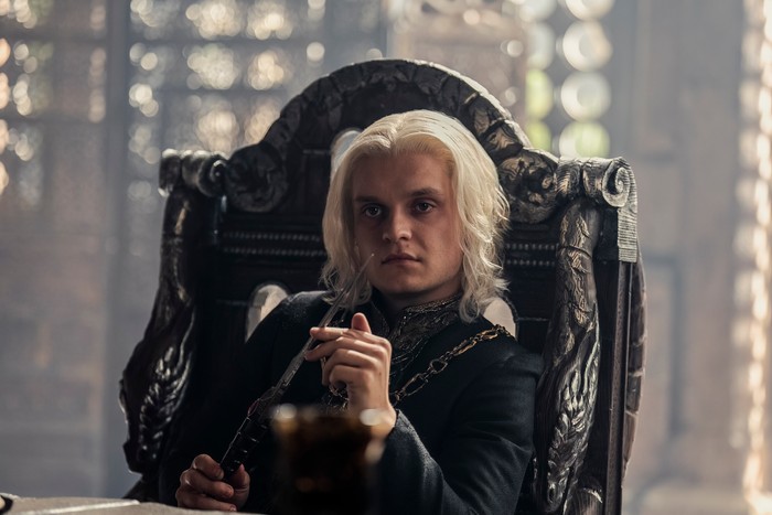 tom-glynn-carney (1) Tom Glynn-Carney sits in a throne as King Aegon II Targaryen in House of the Dragon season 2.